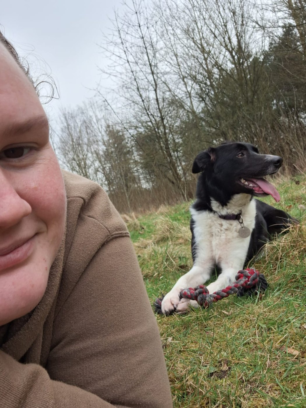 Danielle relaxing outdoors with a black and white dog
