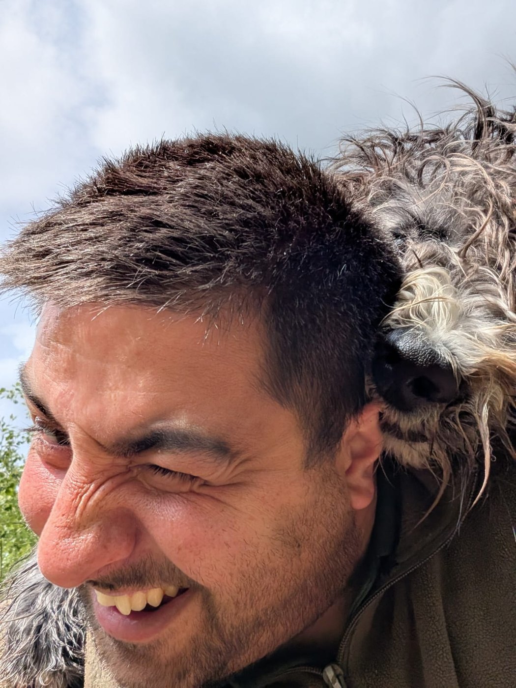 Marcus smiling as a dog rests over his shoulder
